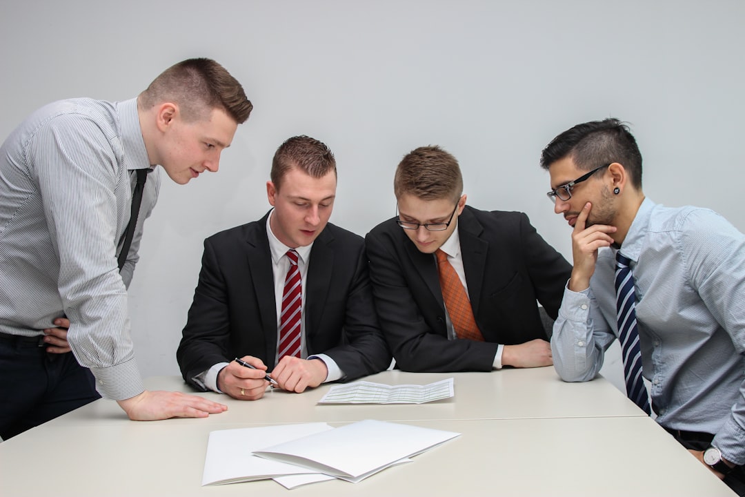 four-men-looking-to-the-paper-on-table-o2o1hzda7ie